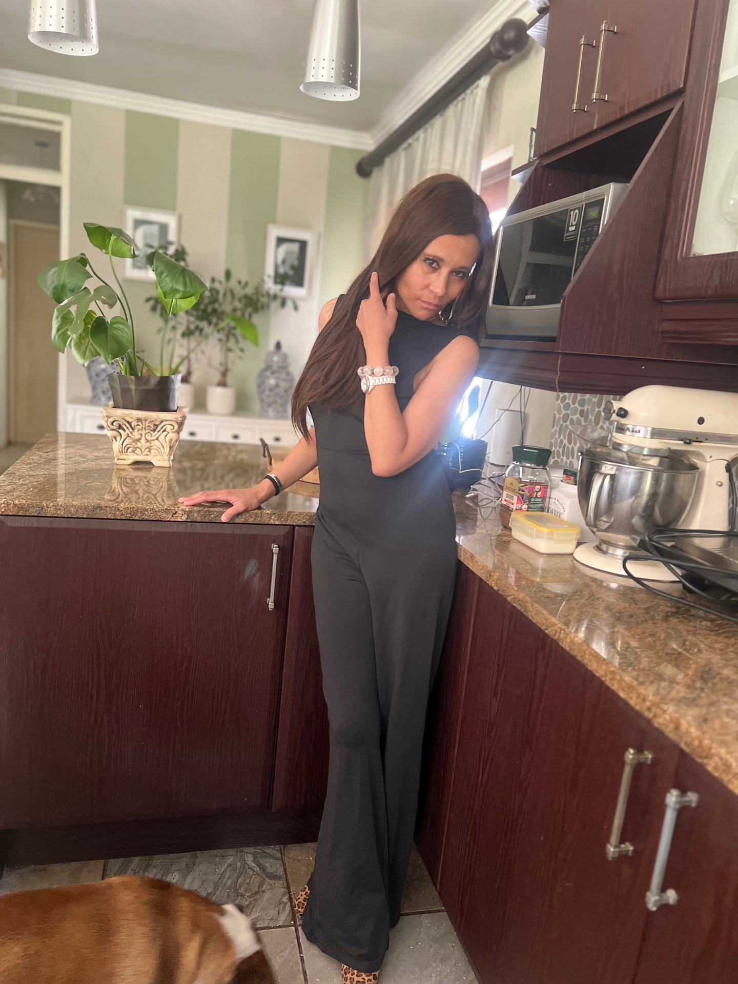 Cass mid-pose in the black bow-back jumpsuit, hand to her hair