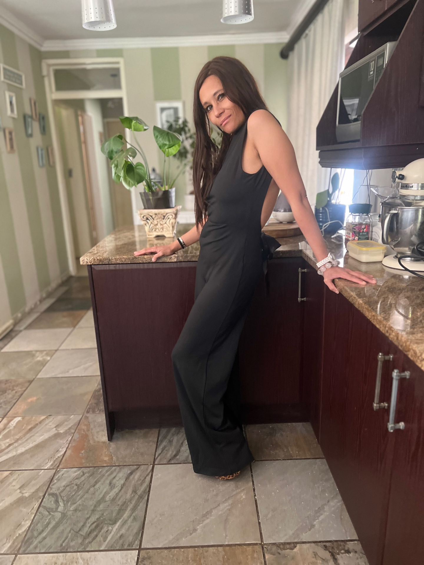 Side profile of Cass in the black jumpsuit showing the wide-leg silhouette and open back