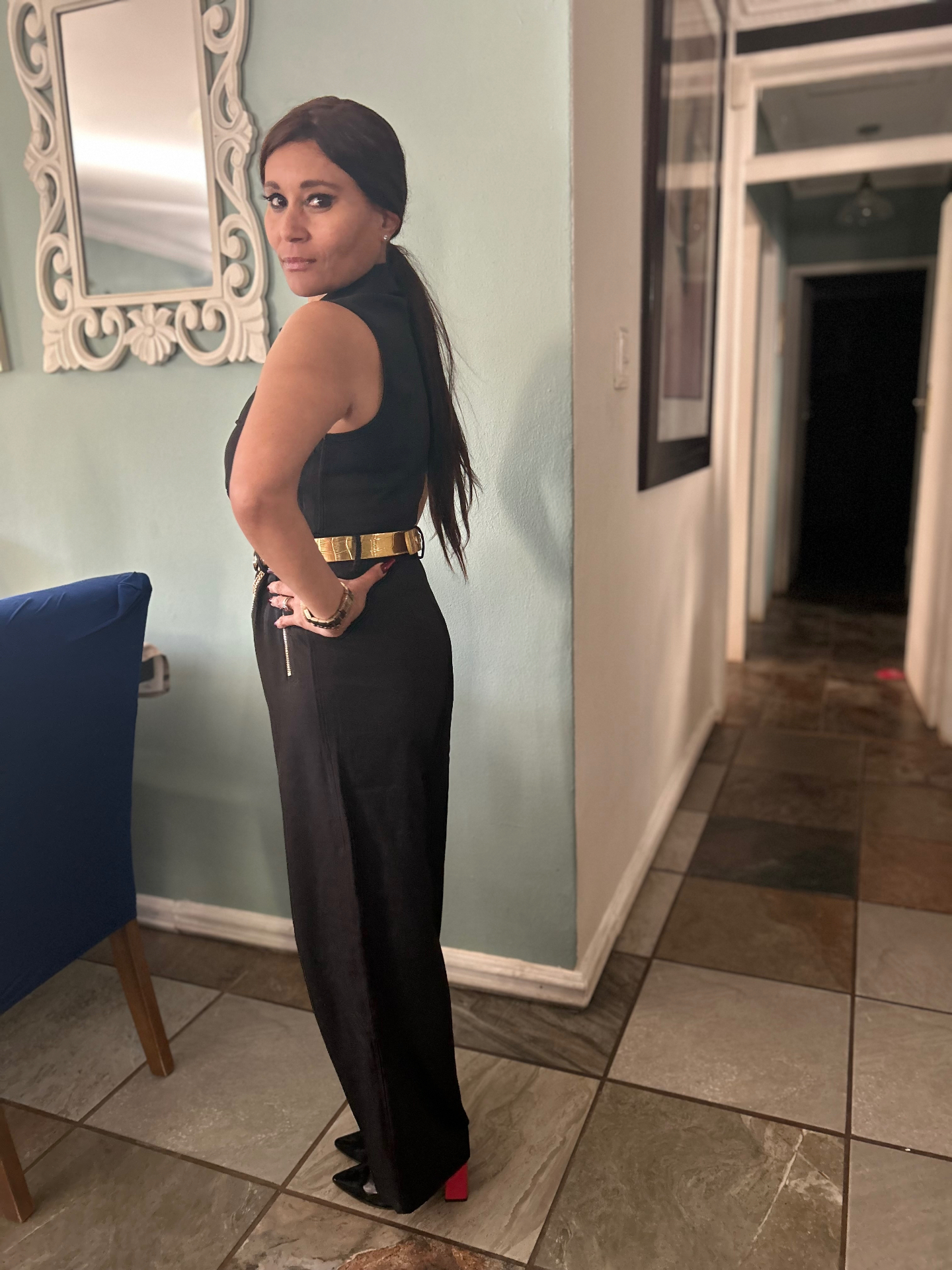 Side and back view of Cass in the black jumpsuit revealing the Brazilian designer shoes with a bright red block heel
