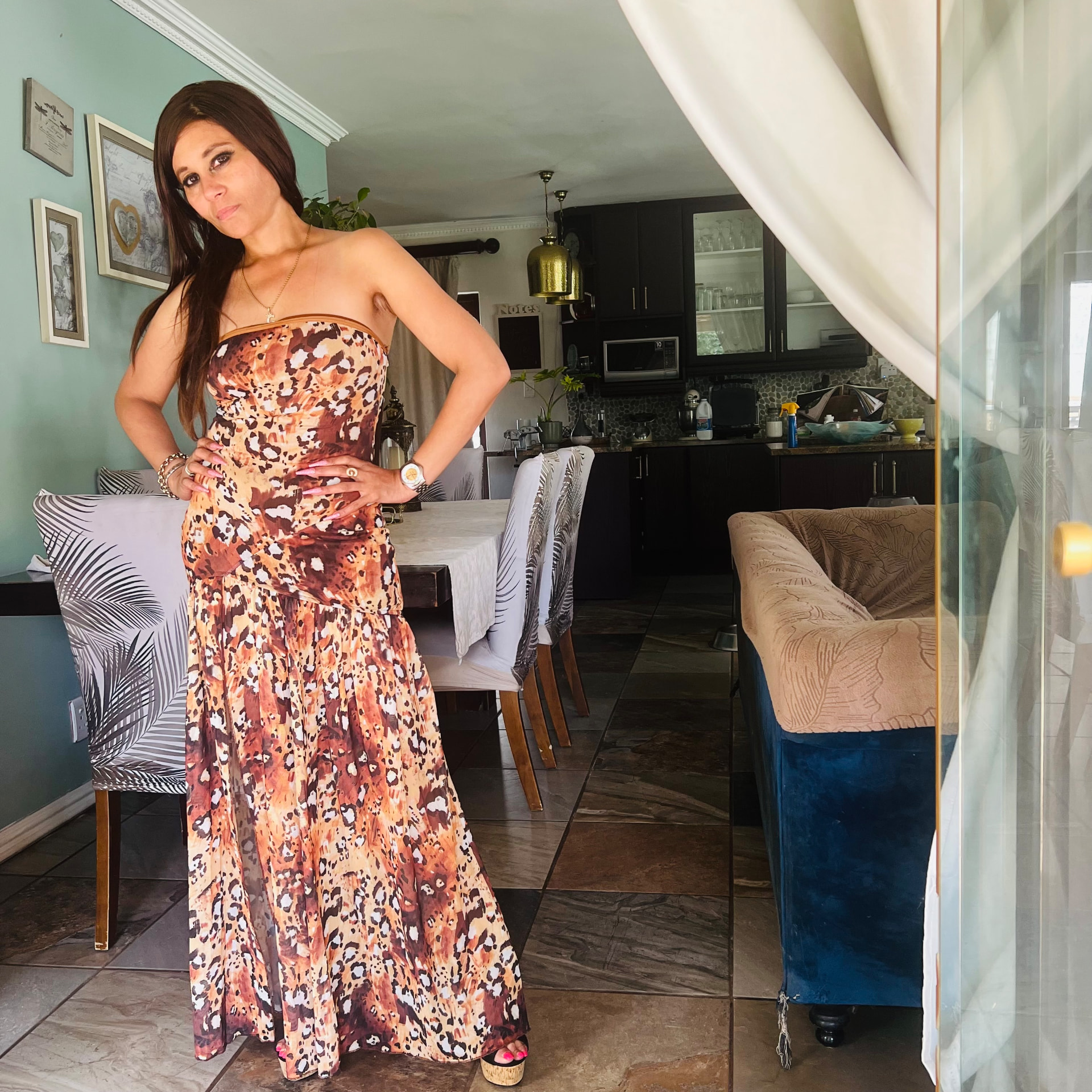 Cass in a strapless leopard-print maxi dress with cork platform heels, hands on hips in a mint green dining room