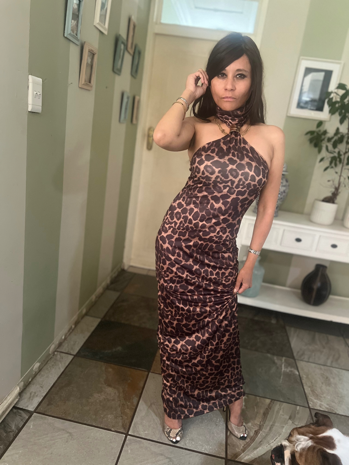Cass in a halter-neck animal-print maxi dress with snake-print mules, standing in a hallway — zero makeup, iPhone mirror selfie by Ntombi