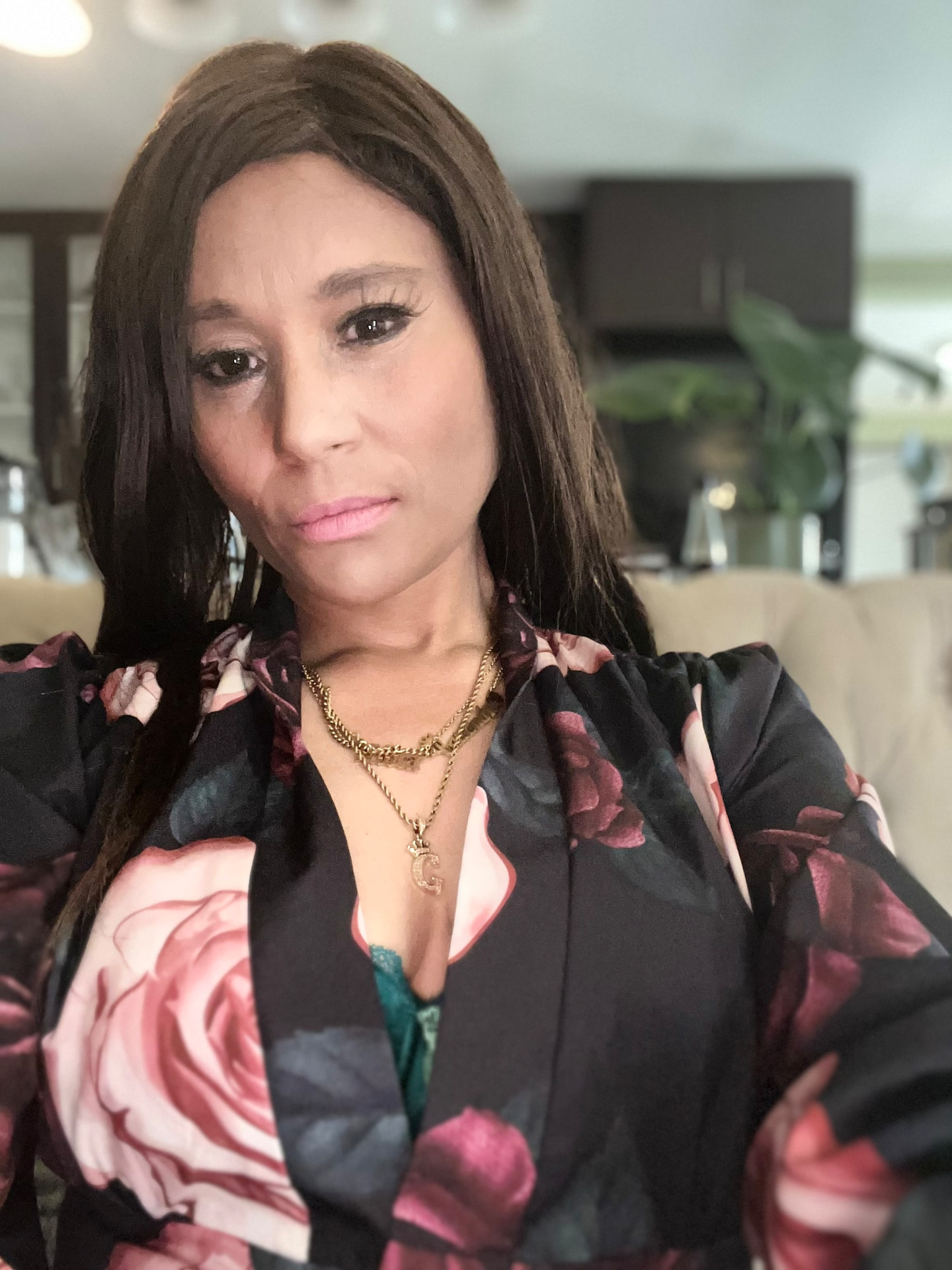 Close portrait of Cass in the dark rose-print blouse with layered gold chains