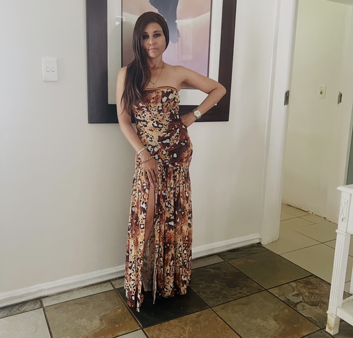 Cass standing full length in the strapless leopard-print maxi dress against a white wall