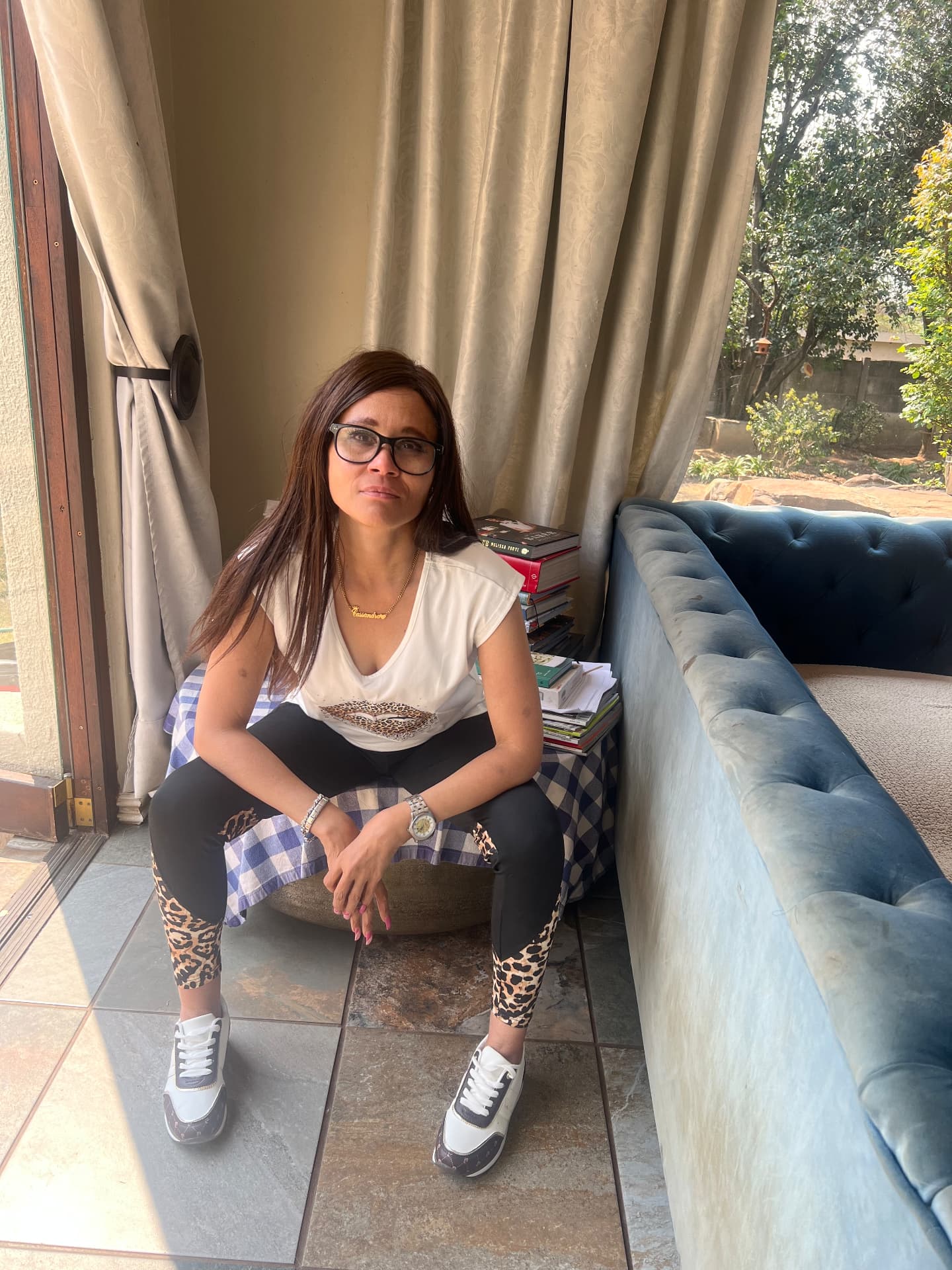 Cass seated in white tee and leopard-panel leggings with Pierre Cardin sneakers