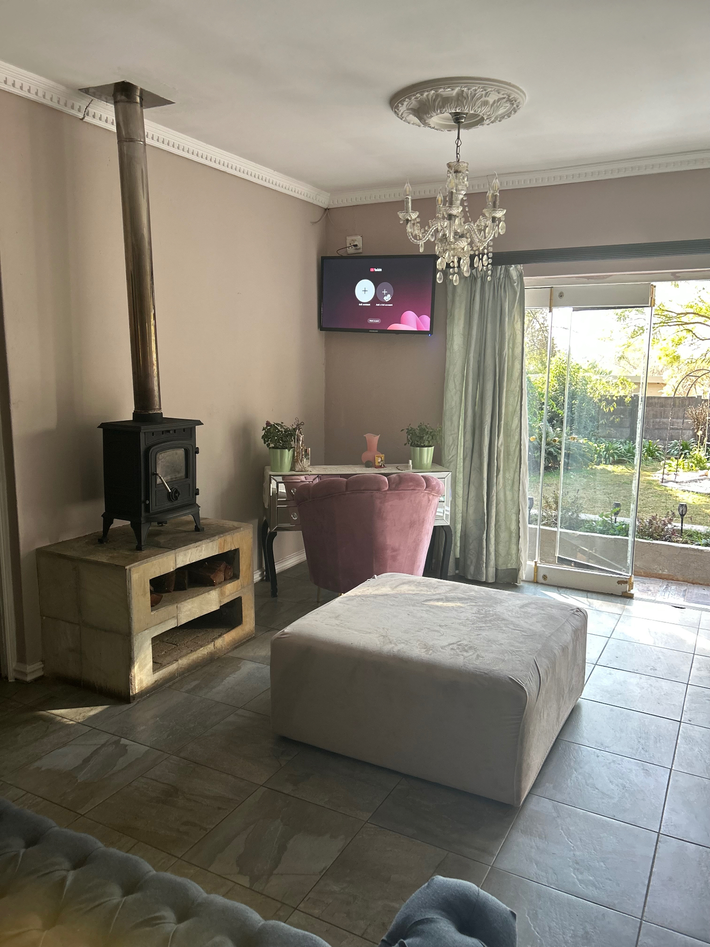 Living space with wood-burning stove, blush pink velvet chair, mirrored console and chandelier