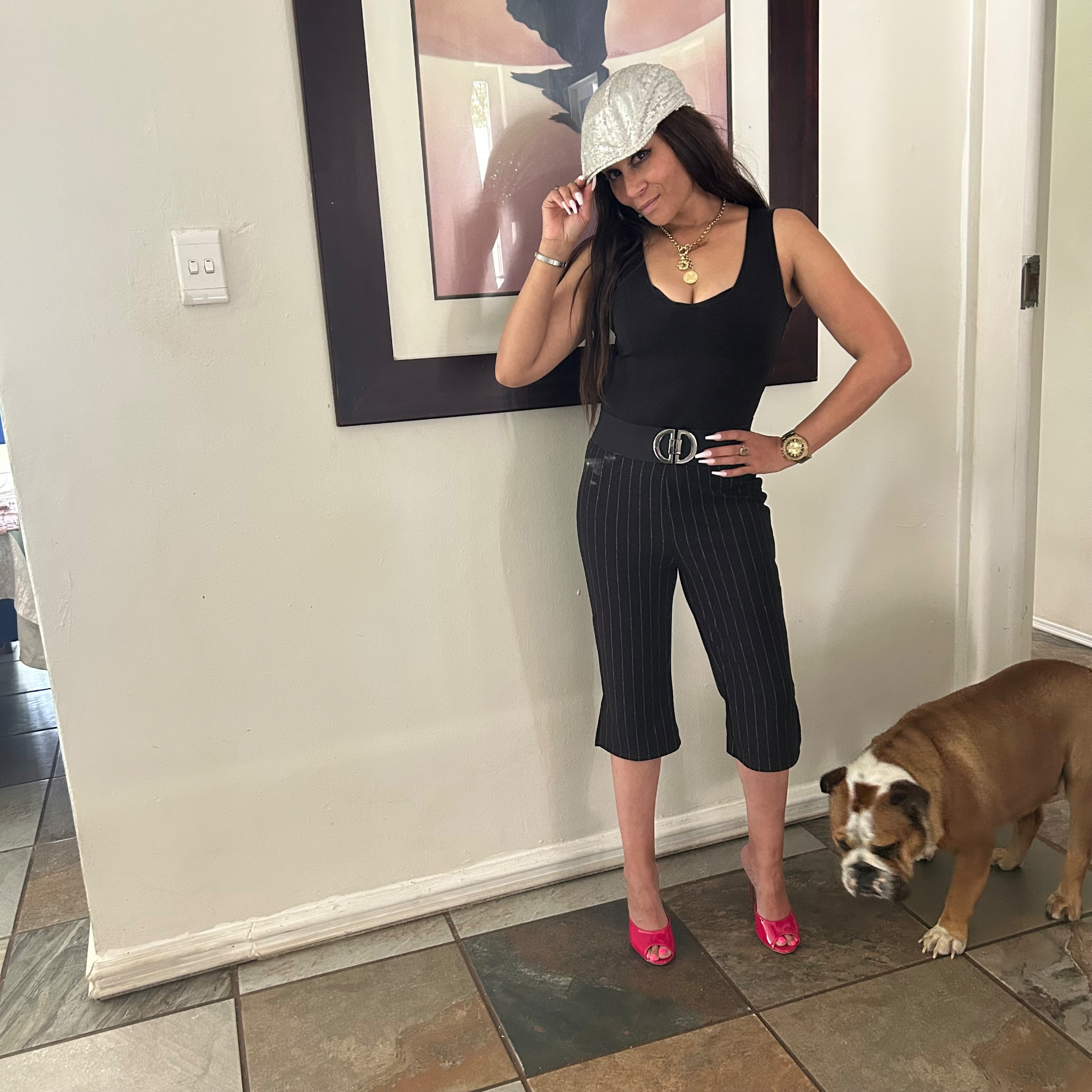 Cass in the sequinned cap and pink heels with a bulldog strolling past her feet
