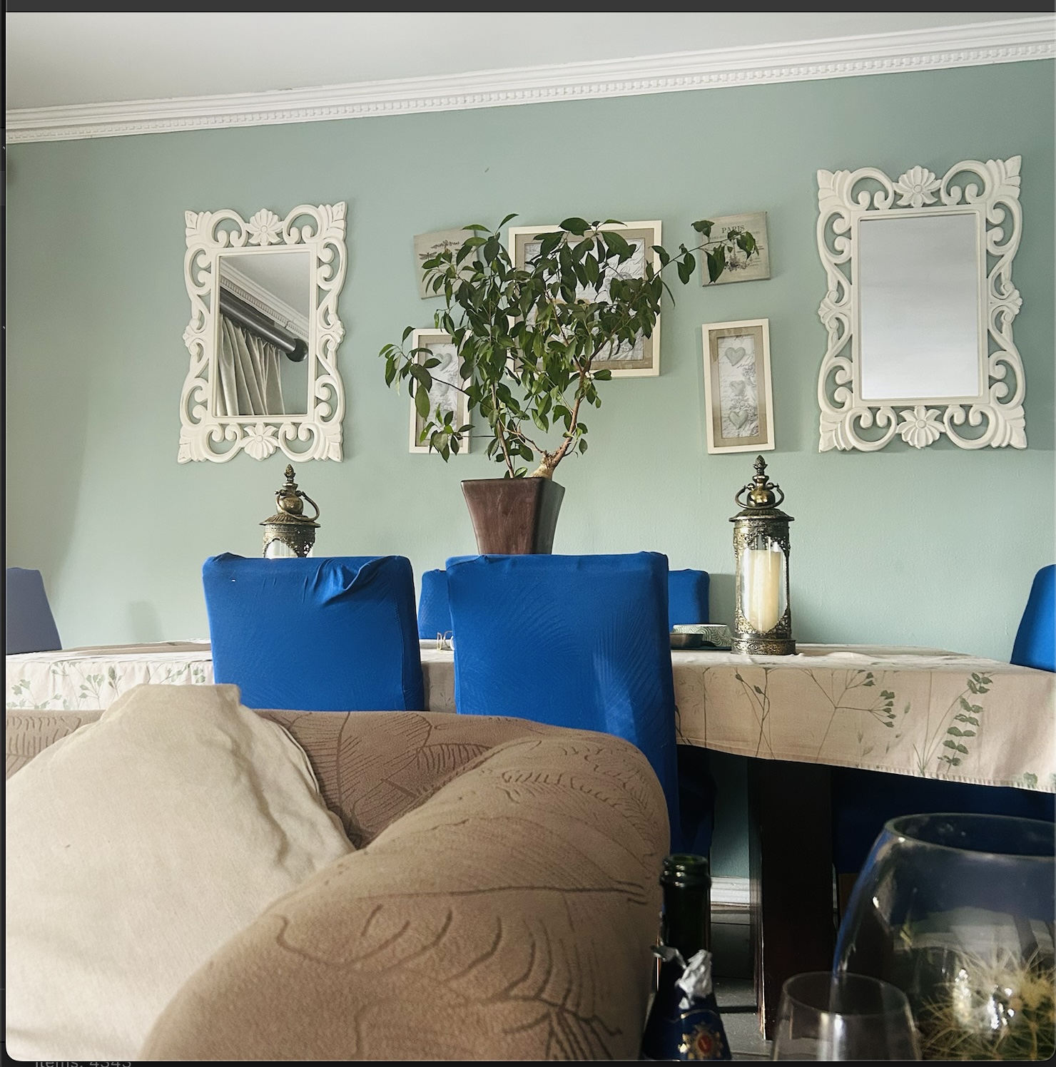 Hamptons-inspired dining area with sage walls, carved white mirrors and blue dining chairs